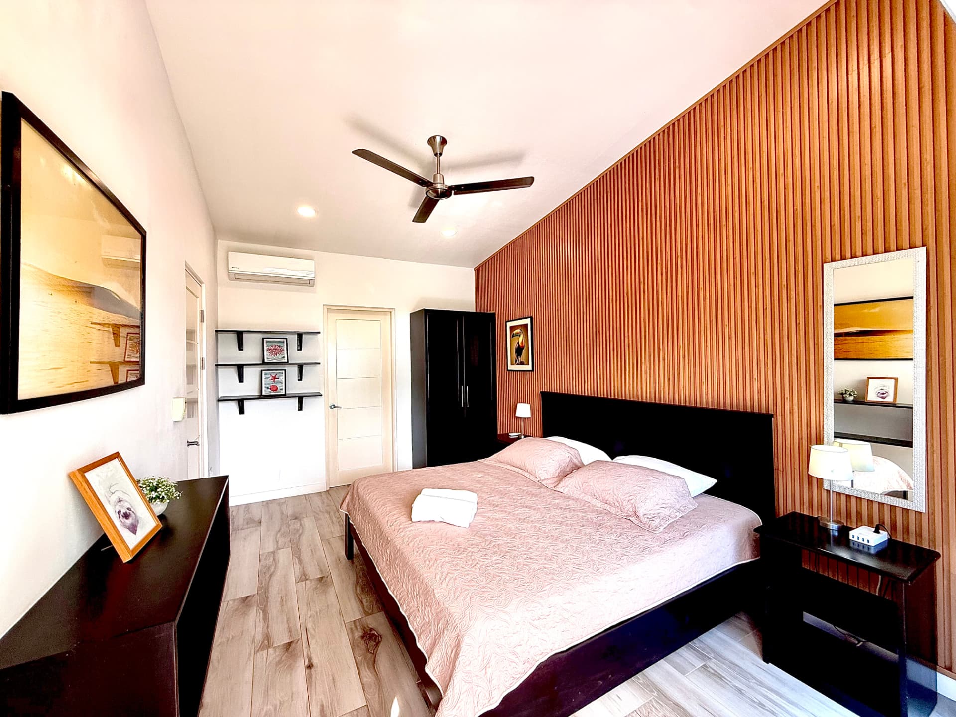 Second view of the primary bedroom with king bed and wood slat accent wall